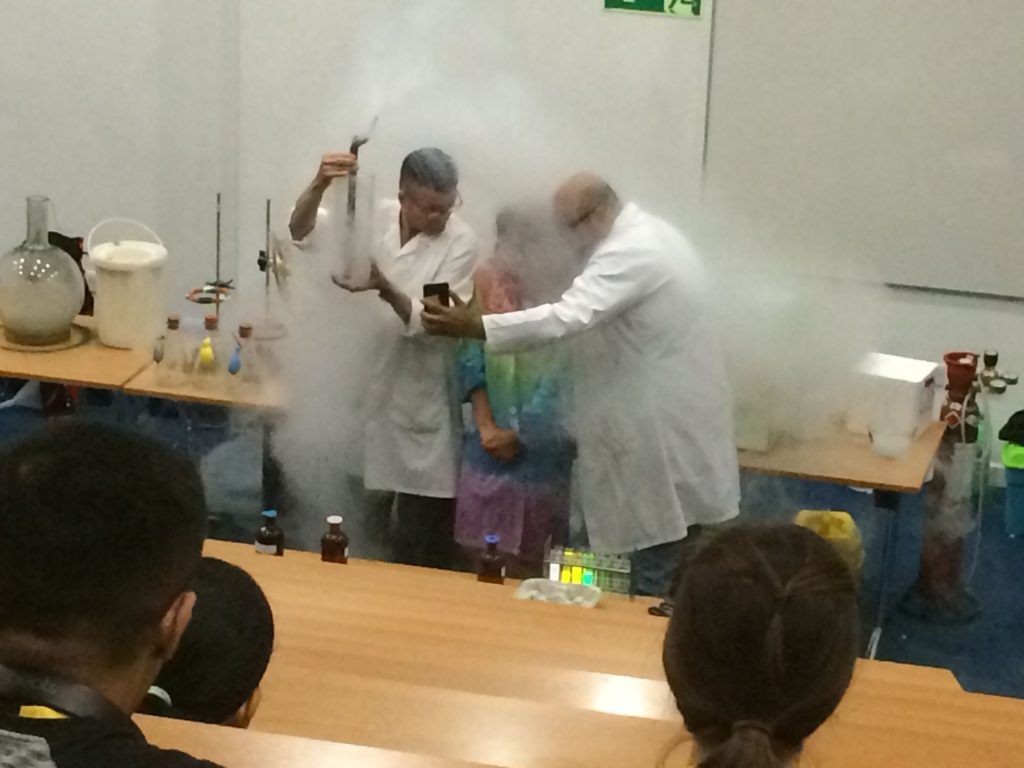 Two scientists in white lab coats hidden by smoke doing an experiment