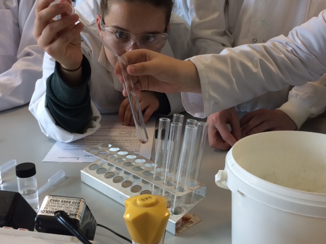 Close up of young people in white lab coats using a pipette and test tube