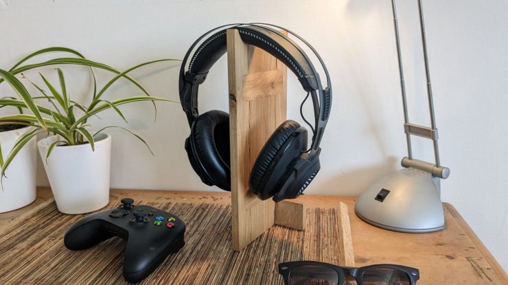 Headphones hooked over a wooden stand on a desk