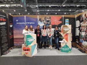 Staff and students standing in front of University of Brighton display stand at a UCAS higher education fair