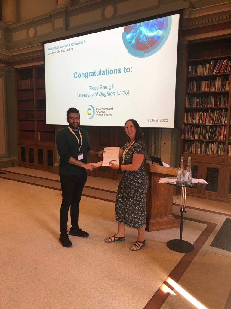 Presentation of award to Ricoveer Shergill and handshake in library with presentation screen