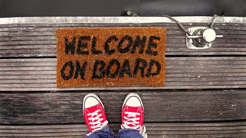 Feet next to doormat which reads welcome on board