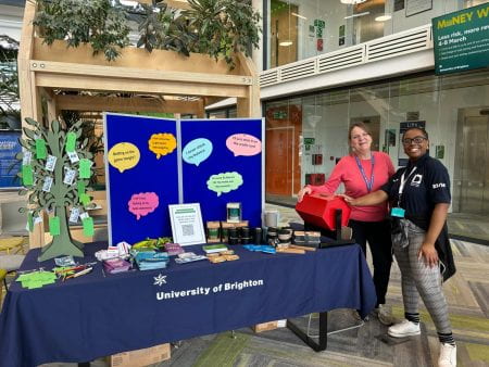 2 people standing at information stall with money advice tips
