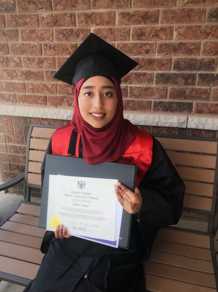 Abeer smiling at the camera with her graduation certificate!