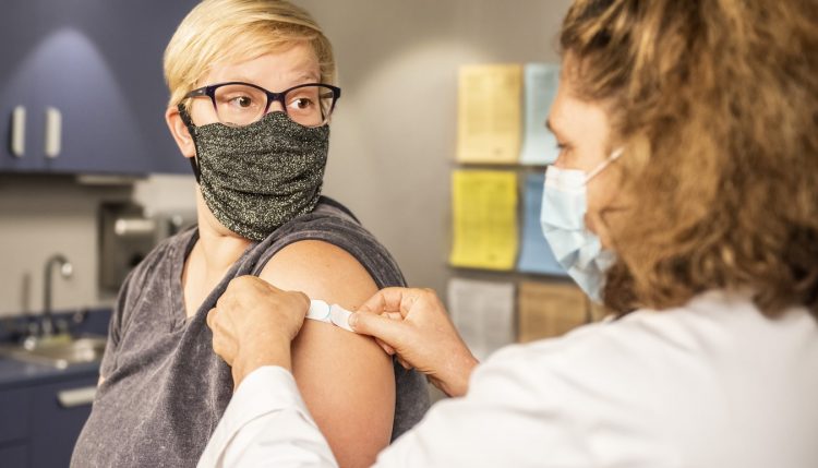 Masked woman after receiving vaccination by doctor