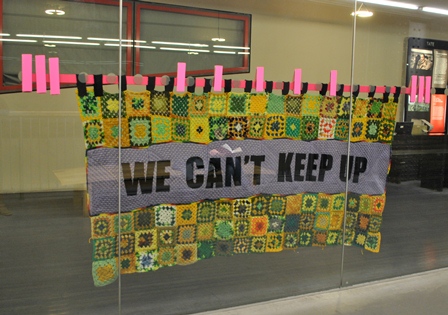 Decorative window banner at Tate Modern reads We can't keep up on a patchwork patterned background