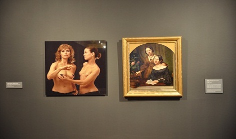Raman Tratsiuk, Lesbian imaginarium. Photograph of grey gallery wall with two images, one a gold framed picture of two seated women in 18th century dress, the other a modern realist painting of two women, naked torsos, one facing the other holding the other's breast, the second facing the viewer. Tanja Ostojić and Marina Gržinić, Politics of Queer Curatorial Positions