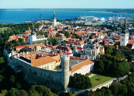 Aerial photograph of Talinn, Estonia, with old town of red roofs and crenelated walls and towers, the sea in the distance.