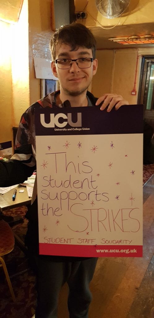 Student holding sign saying "This student supports the strike"