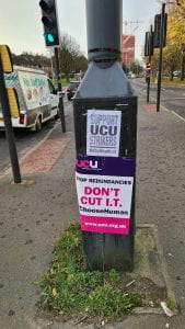 Placards stuck to lamppost. "Don't Cut IT" and "Support UCU"