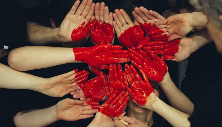hands in the shape of a heart covered in red liquid